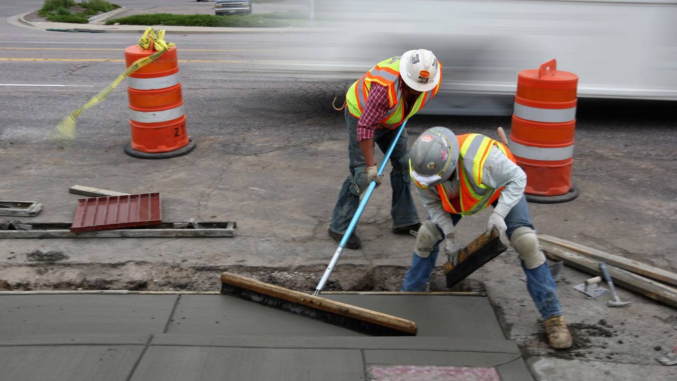 Workers smooth out a new sidewalk