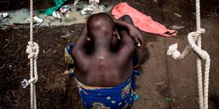 A Internally Displaced Congolese child sits on the ground at a camp for IDP