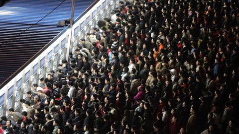 Thousands of Chinese travellers rush to buy their train tickets at the railway station in Beijing