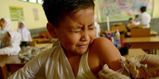 A nurse vaccinates an Indonesian schoolboy