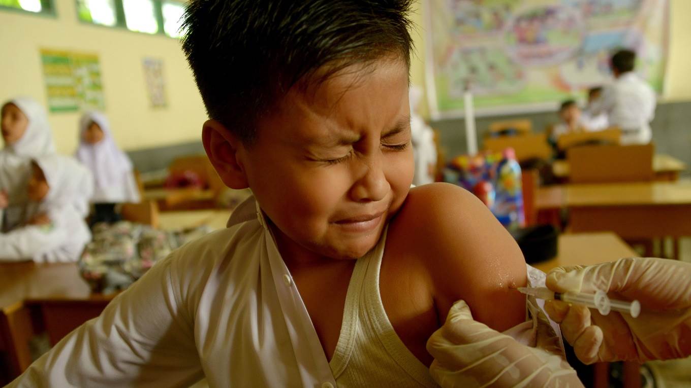 A nurse vaccinates an Indonesian schoolboy